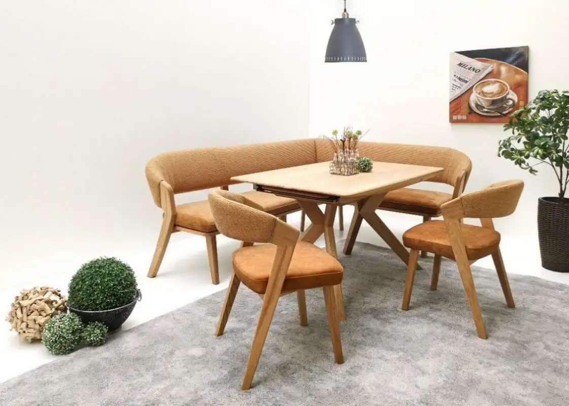 Essgruppe mit einem rechteckigen Holztisch, umgeben von einer gepolsterten Eckbank und drei passenden Stühlen in beige und orange. Die Möbel stehen auf einem grauen Teppich, umgeben von dekorativen Pflanzen und einer Wanddekoration im Hintergrund.